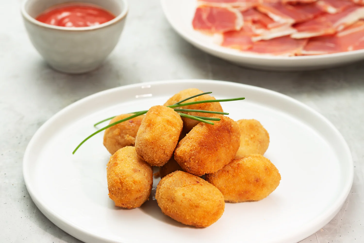 A plate of golden-fried Spanish ham croquettes — croquetas de jamón — with a crispy breadcrumb crust and creamy béchamel filling, served as tapas