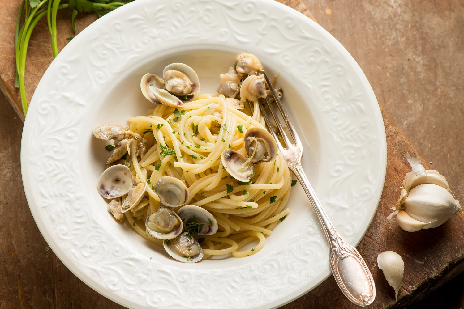 A bowl of spaghetti alle vongole with fresh clams in their shells, tossed in a light white wine, garlic and parsley sauce, served with lemon wedges