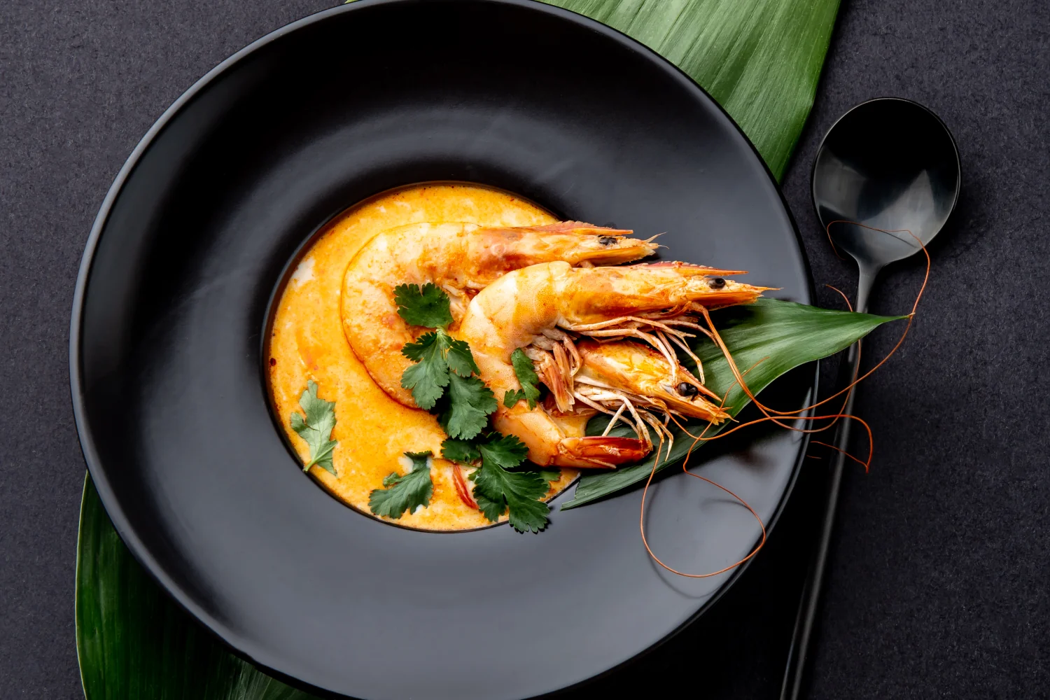A bowl of creamy shrimp bisque garnished with whole prawns, made with homemade shrimp stock, caramelised onions and roasted bell peppers
